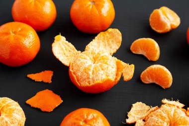 Siyah yüzeyde çiğ organik portakallar, düşük açılı görünüm.