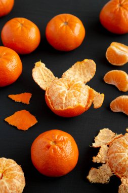 Siyah bir yüzey üzerinde çiğ organik portakallar, yan görünüm.
