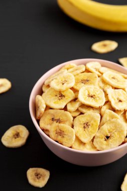 Siyah arka planda, düşük açılı Pembe Kâse 'de ev yapımı muz cipsi.. 
