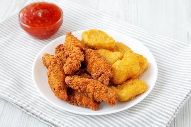 Beyaz ahşap arka planda tatlı ve ekşi soslu ev yapımı Nuggets ve Tavuk Tenders..