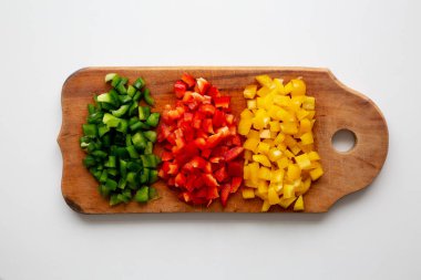 Kırsal ahşap bir tahtanın üstünde doğranmış taze renkli biberler, üst manzara. Dümdüz, tepeden, yukarıdan.