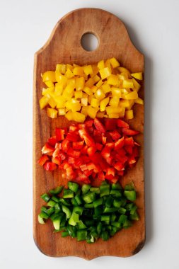 Kırsal ahşap bir tahtanın üstünde doğranmış taze renkli biberler, üst manzara. Dümdüz, tepeden, yukarıdan.