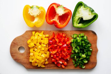 Kırsal ahşap bir tahtanın üstünde doğranmış taze renkli biberler, üst manzara. Dümdüz, tepeden, yukarıdan.