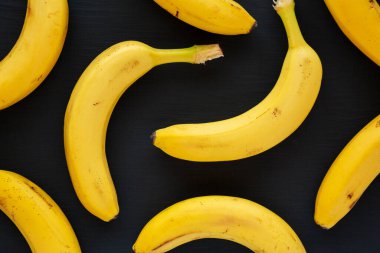 Siyah yüzeyde çiğ organik muzlar, yukarıdan görünüyor. Düz yatıyordu, üstten, yukarıdan..