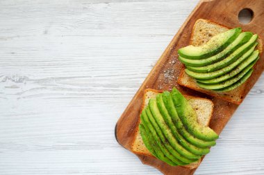 Ev yapımı Avokado tostu, ahşap bir tahtanın üzerinde, üst manzara. Dümdüz, tepeden, yukarıdan. Boşluğu kopyala.