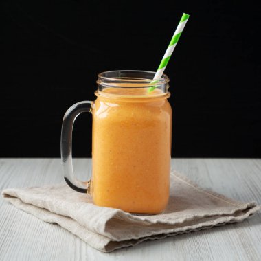 Ev yapımı Havuç Clementine Muz Smoothie Cam Kavanozda; yan görünüm.