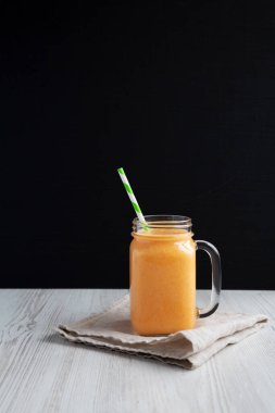 Cam kavanozda ev yapımı havuç Clementine Muzlu Smoothie; yan görüş. Metin için boşluk.