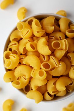 Beyaz arka planda çiğ organik pipo Rigate makarna, üst manzara. Dümdüz, tepeden, yukarıdan. Yakın plan..