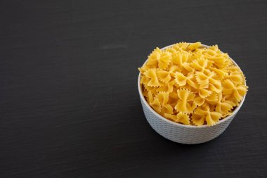 Siyah arka planda bir kasede çiğ organik Farfalle Makarnası. Boşluğu kopyala.