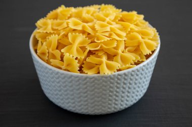 Siyah arka planda bir kasede çiğ organik Farfalle Makarnası. Yakın plan..