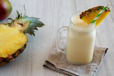 Ev yapımı Pineapple Mango Muzlu Smoothie cam kavanozda, düşük açılı..  