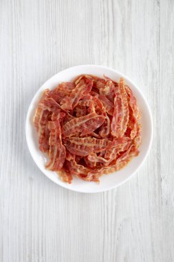 Beyaz bir tabakta beyaz ahşap arka planda kızarmış pastırma, üst manzara. Dümdüz, tepeden, yukarıdan. 
