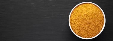 Kahverengi Demerara Şekeri, siyah bir yüzey üzerinde bir kasede, üst manzara. Dümdüz, tepeden, yukarıdan. Metin için boşluk.