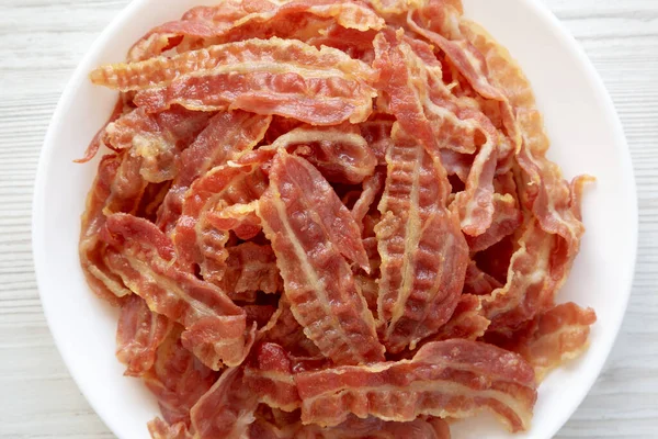 Beyaz bir tabakta beyaz ahşap arka planda kızarmış pastırma, üst manzara. Dümdüz, tepeden, yukarıdan. 