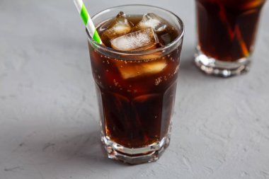 Soğuk Tazeleyen Koyu Kola gri arka planda, düşük açı görünümlü buz küpleriyle. 