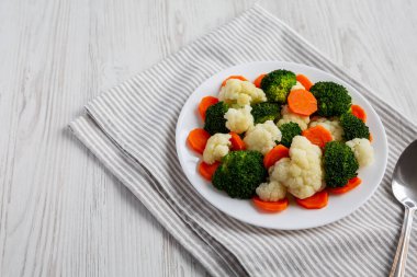 Beyaz ahşap bir zemin üzerinde, havuç, brokoli ve karnabahar gibi karışık organik sebzeler. Boşluğu kopyala.