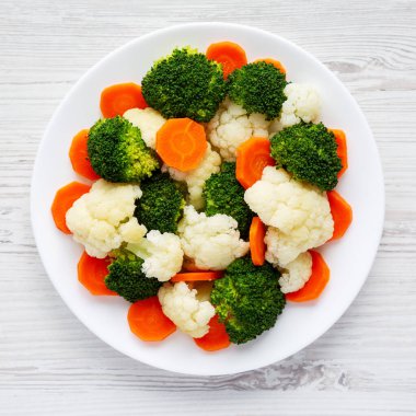 Beyaz ahşap bir zemin üzerinde, havuç, brokoli ve karnabahar gibi karışık organik sebzeler. Dümdüz, tepeden, yukarıdan. 