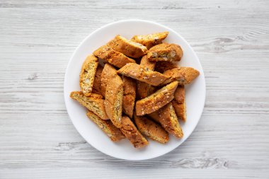 Beyaz ahşap arka planda, badem kaplı ev yapımı İtalyan Cantuccini. Çıtır bademli kurabiyeler. Dümdüz, tepeden, yukarıdan. 