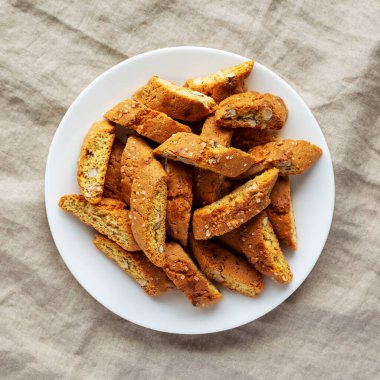 Beyaz tabakta badem soslu ev yapımı İtalyan Cantuccini. Çıtır bademli kurabiyeler. Dümdüz, tepeden, yukarıdan. 