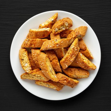 Siyah arka planda badem kaplı ev yapımı İtalyan Cantuccini. Çıtır bademli kurabiyeler. Dümdüz, tepeden, yukarıdan. 