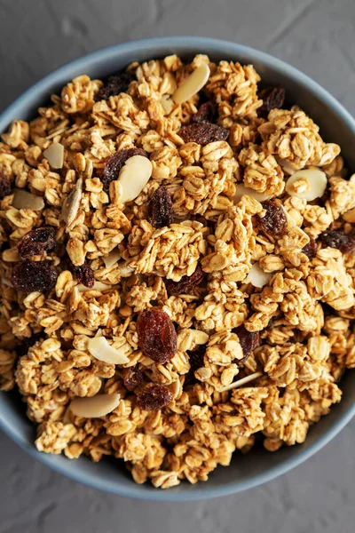 Gri arka planda, kuru üzüm ve bademli ev yapımı granola. Dümdüz, tepeden, yukarıdan.