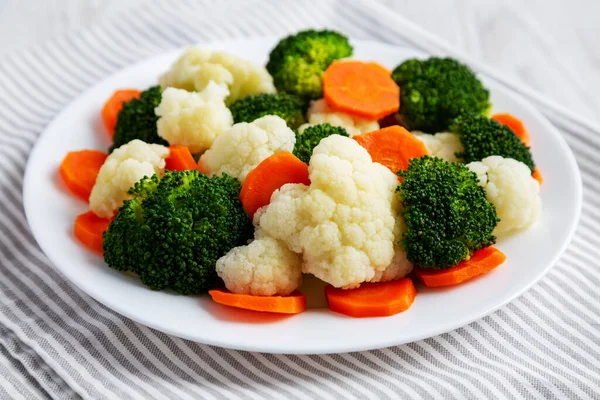 Beyaz ahşap bir arka planda, havuç, brokoli ve karnabahar gibi karışık organik sebzeler. Yakın plan..