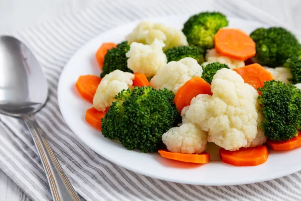 Beyaz ahşap bir arka planda, havuç, brokoli ve karnabahar gibi karışık organik sebzeler. Yakın plan..