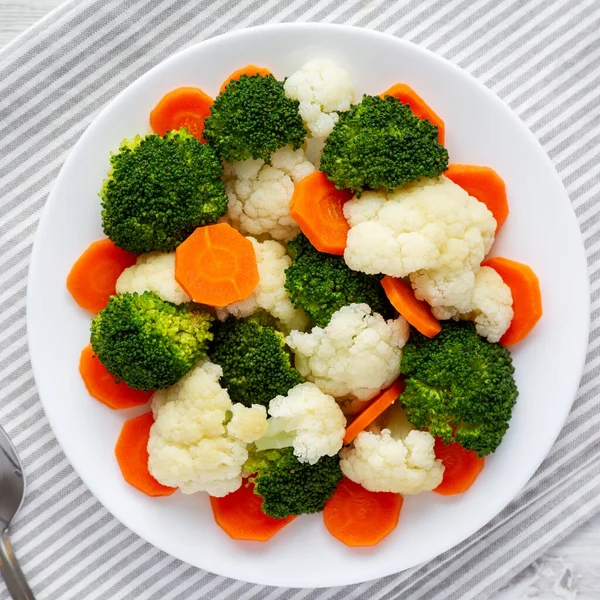 Beyaz ahşap bir zemin üzerinde, havuç, brokoli ve karnabahar gibi karışık organik sebzeler. Dümdüz, tepeden, yukarıdan.