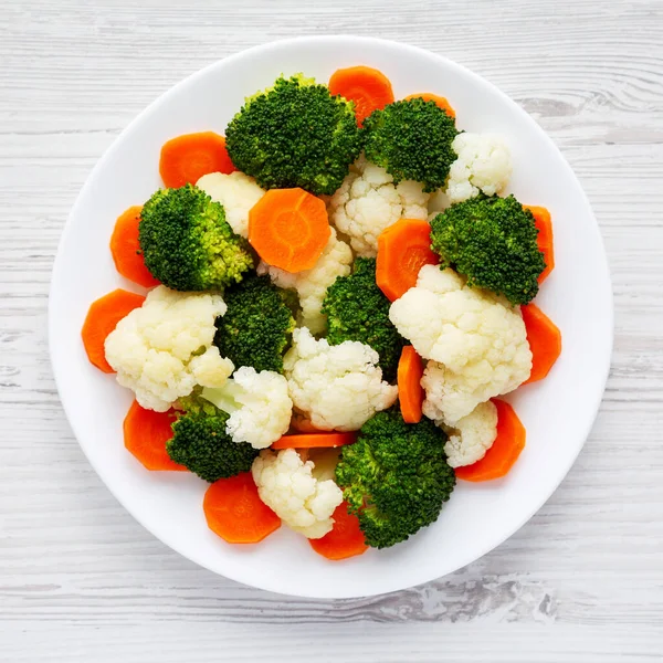 Beyaz ahşap bir zemin üzerinde, havuç, brokoli ve karnabahar gibi karışık organik sebzeler. Dümdüz, tepeden, yukarıdan. 