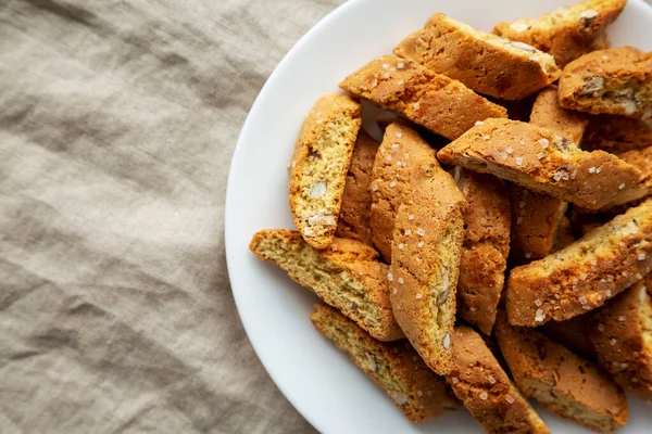 Beyaz tabakta badem soslu ev yapımı İtalyan Cantuccini. Çıtır bademli kurabiyeler. Dümdüz, tepeden, yukarıdan. Boşluğu kopyala.
