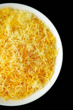 Siyah arka planda, beyaz kasede doğranmış Meksika peyniri karışımı. Dümdüz, tepeden, yukarıdan. 