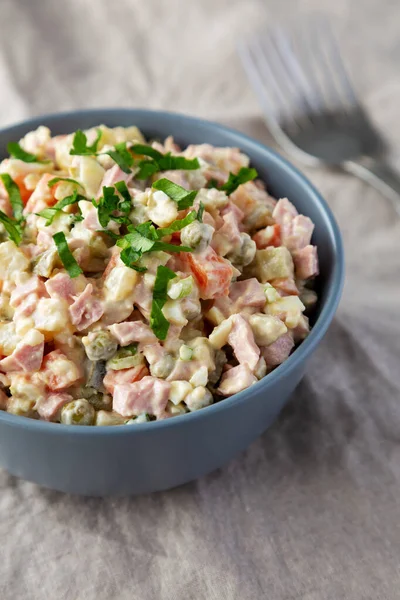 Beyaz ahşap arka planda bir kasede ev yapımı Olivier salatası.. 