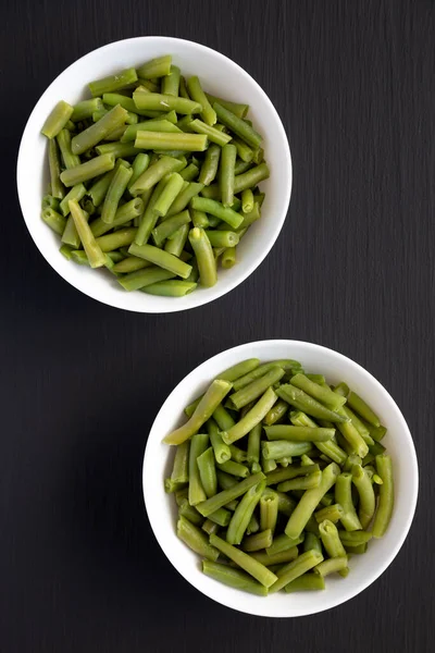 Siyah bir yüzey üzerinde, Beyaz Kasede Buharlı Yeşil Fasulye, üst manzara. Yukarıdan, dümdüz uzanmış. 