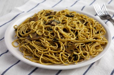 Ev yapımı ıspanaklı mantar soslu spagetti tabakta, düşük açılı. Yakın plan..