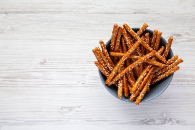 Beyaz ahşap arka planda fırında kraker ve susam çubukları, üst manzara. Dümdüz, tepeden, yukarıdan. Metin için boşluk.