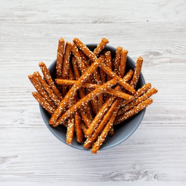 Beyaz ahşap bir yüzey üzerinde fırında kraker ve susam çubukları, üst manzara. Dümdüz, tepeden, yukarıdan. 