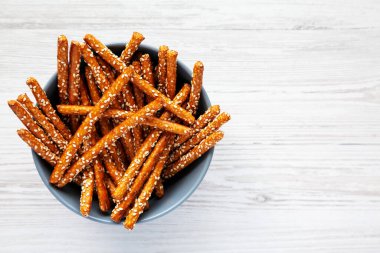 Beyaz ahşap arka planda fırında kraker ve susam çubukları, üst manzara. Dümdüz, tepeden, yukarıdan. Boşluğu kopyala.