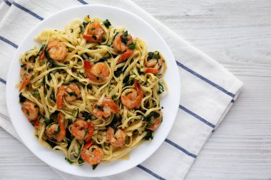 Beyaz ahşap bir yüzey üzerinde tek katlı limonlu sarımsaklı karides makarna. Dümdüz, tepeden, yukarıdan. Boşluğu kopyala.