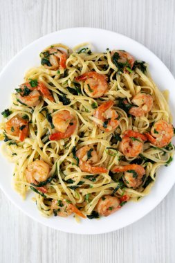 Beyaz ahşap bir yüzey üzerinde tek katlı limonlu sarımsaklı karides makarna. Dümdüz, tepeden, yukarıdan.