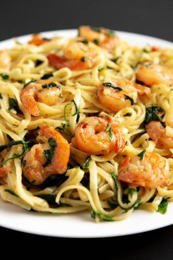 Ev yapımı limonlu sarımsaklı karidesli makarna. Siyah bir tabakta..