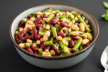 Siyah arka planda, bir kasede üç fasulye salatası.. 