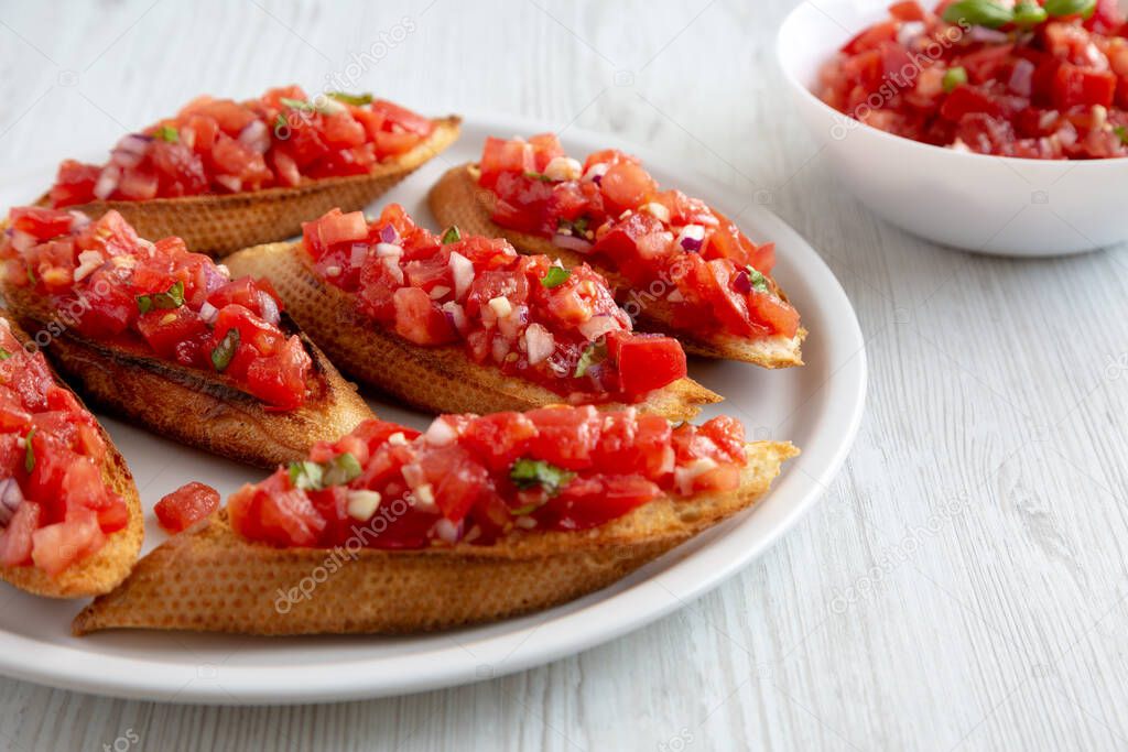 Homemade Italian Tomato Bruschetta with Basil on a Plate, side view. Close-up.