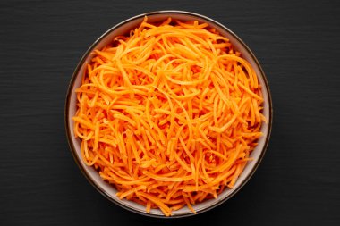 Siyah arkaplandaki çiğ turuncu havuç parçacıkları, üst manzara. Yukarıdan, dümdüz uzanmış. 