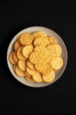 Siyah arka planda tuzlu yuvarlak krakerler, üst manzara. Dümdüz, tepeden, yukarıdan. 