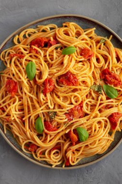 Gri bir yüzeyde taze domates soslu ev yapımı spagetti makarna, üst manzara. Dümdüz, tepeden, yukarıdan.