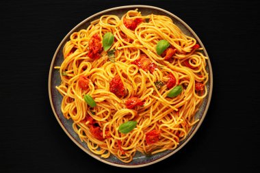 Siyah bir tabakta taze domates soslu ev yapımı spagetti makarna, üst manzara. Dümdüz, tepeden, yukarıdan. 
