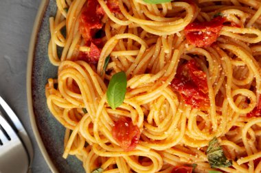 Gri bir yüzeyde taze domates soslu ev yapımı spagetti makarna, üst manzara. Dümdüz, tepeden, yukarıdan. Yakın plan..