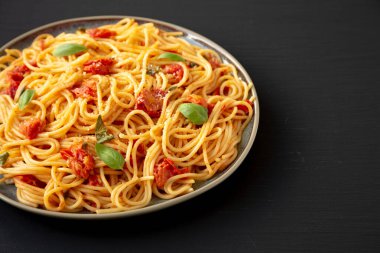 Siyah bir tabakta taze domates soslu ev yapımı spagetti makarna.. 