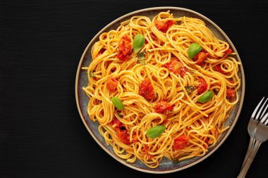 Siyah bir tabakta taze domates soslu ev yapımı spagetti makarna, üst manzara. Dümdüz, tepeden, yukarıdan. Boşluğu kopyala.