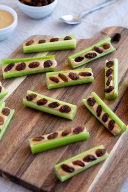 Kereviz, fıstık ezmesi ve ahşap bir tahtanın üzerinde kuru üzümlü ev yapımı karınca..